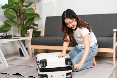 Travel Preparation. Young woman packing suitcase with excitement for upcoming trip.の写真素材
