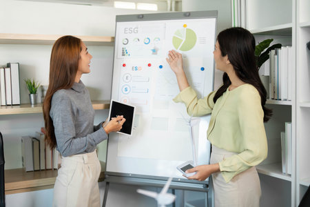 ESG Planning. Women analyzing data for sustainability initiatives in a modern workspace.の写真素材