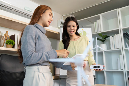 ESG Collaboration. Business professionals discussing renewable energy solutions with wind turbine model.の写真素材