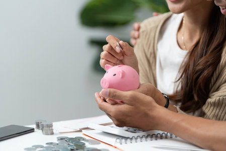 Financial Empowerment Through Budgeting. Couple holding a piggy bank while discussing savings.の写真素材
