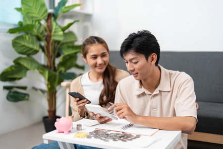 Financial Planning and Budgeting. Young couple managing expenses with smartphone and calculator at home.の写真素材