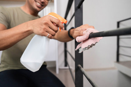 Home Cleaning and Maintenance. A man actively cleaning a railing with a spray bottle and cloth.の写真素材
