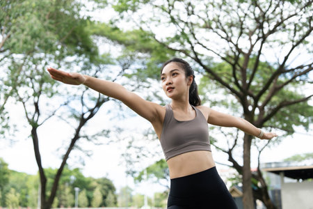 Yoga in nature. Woman practicing a yoga pose with focus and grace in a park.の写真素材