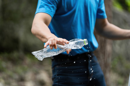 Volunteer in action. Individual splashing water while discarding plastic bottle.