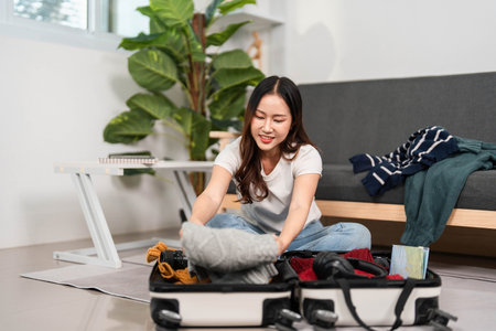 Travel Preparation. Young woman packing suitcase with clothes and essentials for a trip.の写真素材