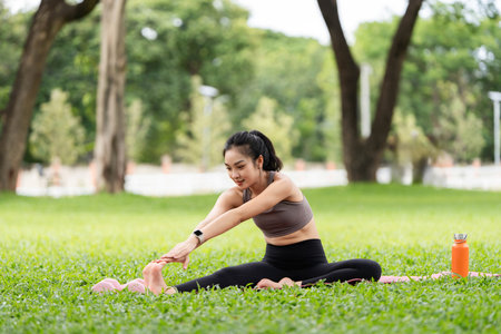 Outdoor yoga practice. Young woman stretching her legs on a yoga mat in a park.の写真素材