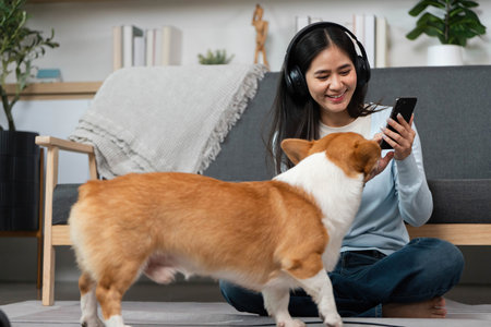 Pet Interaction and Digital Connection. Woman smiling while using smartphone as her dog approaches.の写真素材