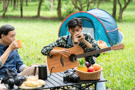 Family bonding outdoors. Father and son enjoying music and coffee in nature.の写真素材