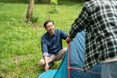 Family bonding during camping. Father and son setting up a tent in the park.の写真素材