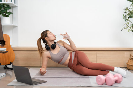 Yoga and Wellness. Woman practicing yoga and hydrating at home.の写真素材