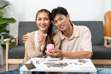 Couple Sharing Savings Success: Managing Coins and Piggy Bank Togetherの写真素材