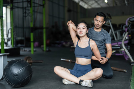 Personal Training and Fitness Coaching. A trainer assisting a woman with stretching exercises in a gym.の写真素材
