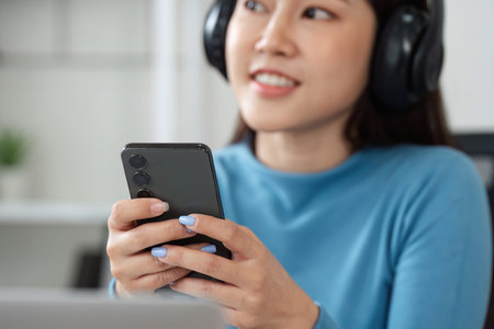 Music and Relaxation. A woman enjoying music on her smartphone while using headphones.の写真素材