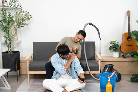 Supportive cleaning interaction. Friends enjoying a playful moment while cleaning together.の写真素材