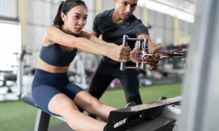Fitness Trainer Assisting Client with Rowing Machine Workout