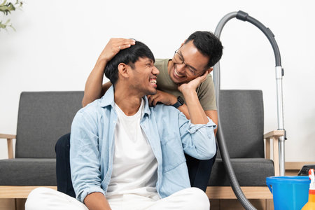 Affectionate Couple Sharing a Laugh During Home Cleaning. Joyful moments while vacuuming.の写真素材