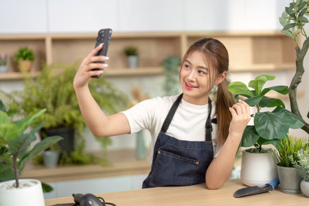 Selfie Moment in Nature. Young woman taking a selfie in a lush indoor garden with plants.の写真素材