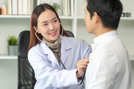 Healthcare Professional. Female doctor examining male patient with stethoscope.の写真素材