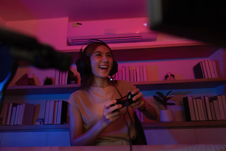 Gaming and Digital Entertainment. Young woman enjoying video games in a vibrant, colorful setting.の写真素材