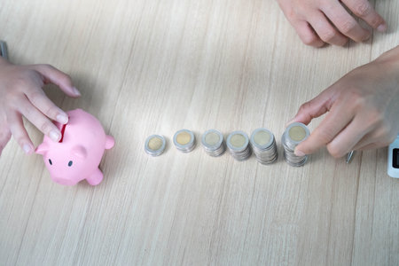 Financial Empowerment and Budgeting. Young couple managing savings with piggy bank and coins.