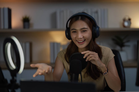Remote Work and Digital Communication. Young woman actively participating in a video call with a microphone.の写真素材