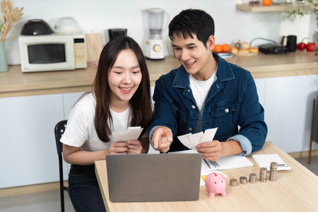 Couple Reviewing Finances on Laptop. Young adults discussing savings and investments.の写真素材