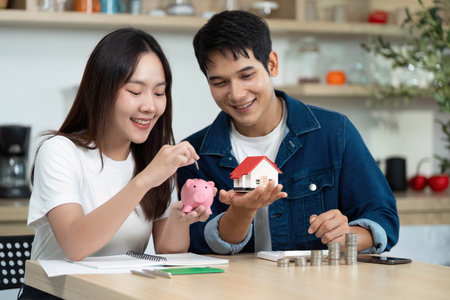 Financial Planning and Budgeting. Young couple managing savings with piggy bank and house model.の写真素材