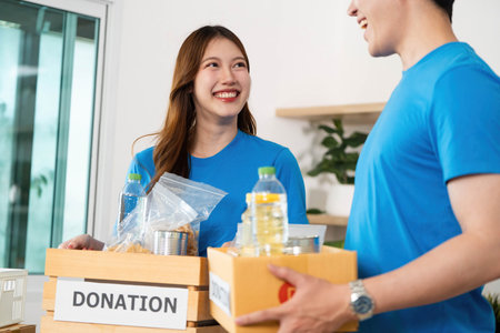 Donation and Community Support. Volunteers packing food items for donation in a cheerful environment.の写真素材