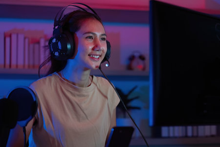 Joyful Gamer Engaged in Gameplay. Young woman smiling while gaming with headset.