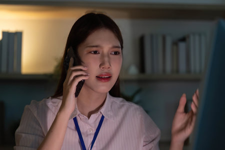 Stressful Situation. Young woman on phone, expressing concern in modern office.の写真素材