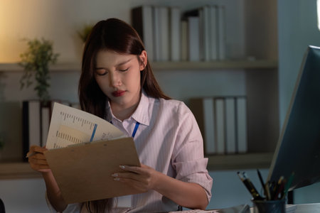 Detailed Review. Young woman analyzing documents in a modern office.の写真素材