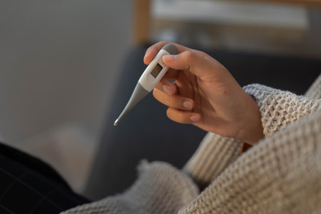 Fever Monitoring. Individual checking temperature with thermometer.