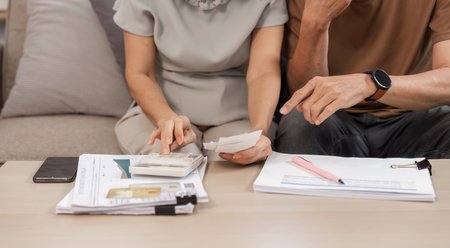 Elderly Couple Collaborating on Family Financial Planning at Home with Documents and Calculator