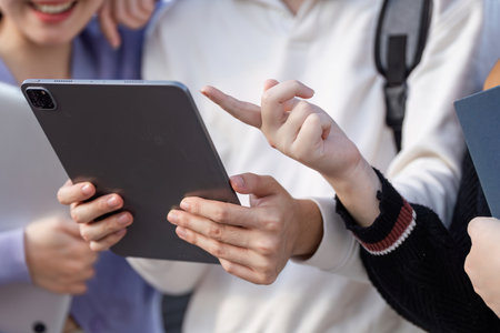 Diverse Group of Students Engaged in Online Learning Outdoors with Digital Devices and Books