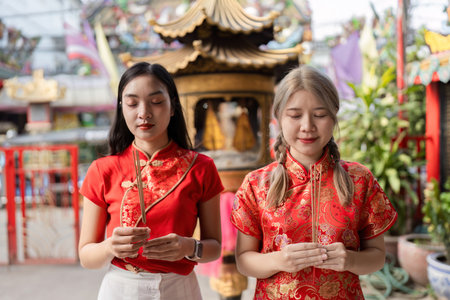Celebrating chinese new year two women in traditional attire temple setting cultural ritual vibrant...
