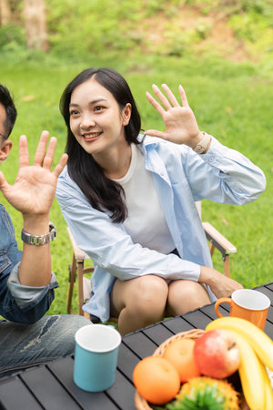 Happy couple waving and enjoying healthy snacks in a sunny garden.の写真素材