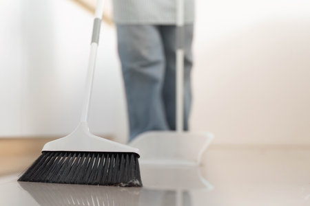 Floor Cleaning. Close-up of broom sweeping the floor, maintaining cleanliness.