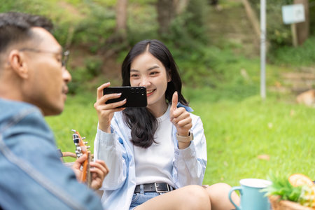 Outdoor Fun. Young woman capturing joyful moment with smartphone in nature.の写真素材