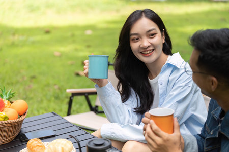 Couple enjoying drinks and laughter in a sunny gardenの写真素材