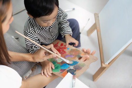 Mother Assisting Child with Color Mixing in Art Classの写真素材