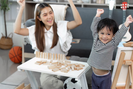 Celebration of Achievement. Child and mother rejoice after building with wooden blocks.の写真素材