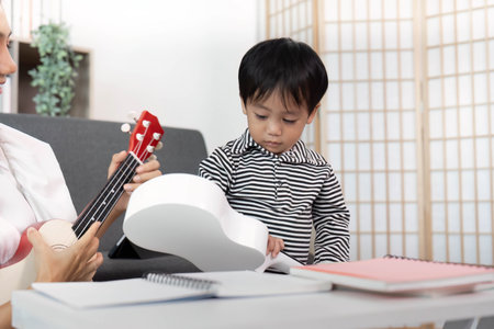 Creative Learning. Child Exploring Ukulele with Mother in Cozy Settingの写真素材