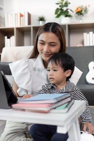 Focused Learning. Child Watching Tablet with Mother in Cozy Living Roomの写真素材