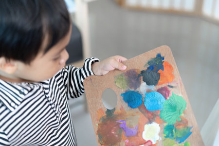 Child Holding Colorful Palette After Painting Sessionの写真素材