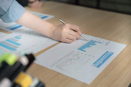 Accounting Analysis. Professional hand reviewing financial graphs and data on documents.