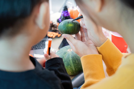 Halloween Family Time. Adult and child painting pumpkins together in a festive atmosphere.の写真素材