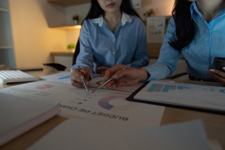 Team Analysis. Close-up of two professionals reviewing budget charts and data in a collaborative workspace.の写真素材