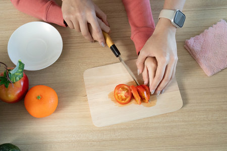 Healthy Cooking. Close-up of mother and son slicing fresh tomatoes together.