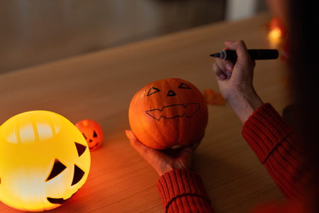 Pumpkin Carving. Woman creating spooky designs on Halloween pumpkin.の写真素材