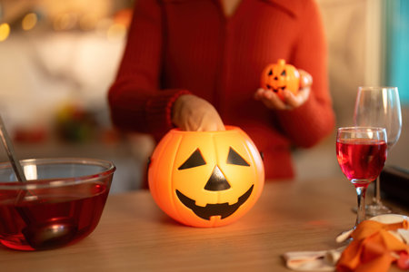 Halloween Fun. Woman preparing spooky treats with pumpkin decorations.の写真素材